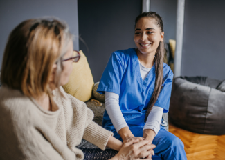 Happy caregiver and senior speaking on the couch