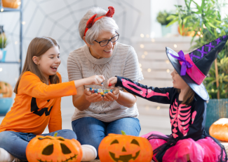 Senior and grandchildren eating candy on Halloween