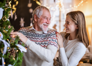 Senior man and granddaughter decorating Christmas tree together