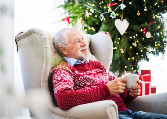 Happy senior at home during the winter, enjoying a hot drink and relaxing