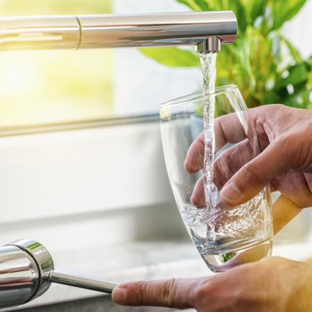 Caregiver pouring glass of water for senior, helping them stay hydrated through the summer
