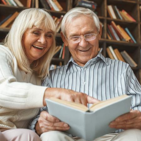Seniors reading a book together at their local library