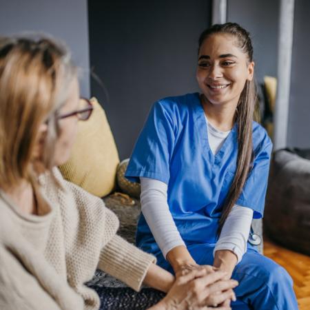 Happy caregiver and senior speaking on the couch